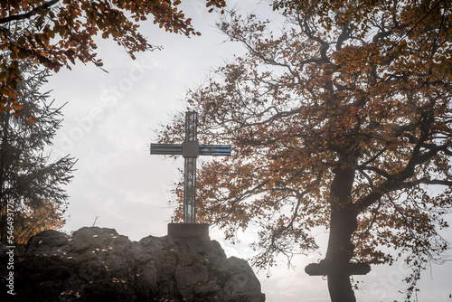 A glass cross on a stone in the perfect light and beautiful trees in the background  photo