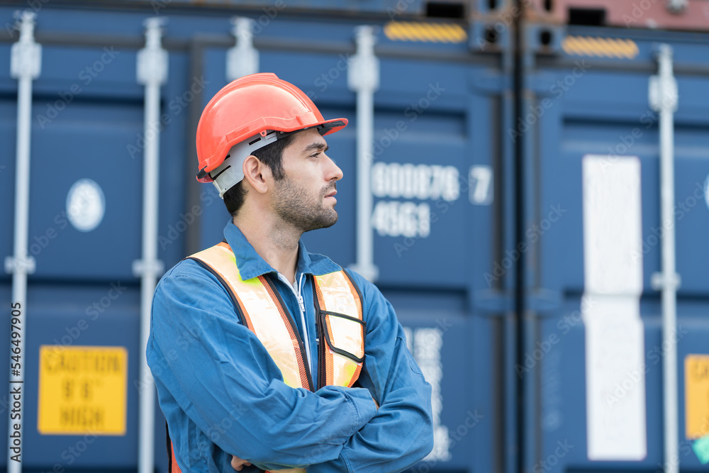 Portrait of male container yard worker working at commercial dock site. Male supervisor container yard worker wear safety helmet, uniform working at container terminal yard Portrait of male container yard worker working at commercial dock site. Male supervisor container yard worker wear safety helmet, uniform working at container terminal yard