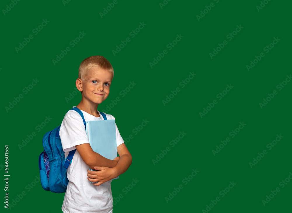 Boy with smile, with book in his hands and backpack on his back. Future student, successful student, happy child. Green background with space for text. Selective focus. Boy with smile, with book in his hands and backpack on his back. Future student, successful student, happy child. Green background with space for text. Selective focus.