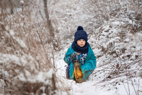 A little boy plays with the snow, rejoices in the snow and carries his flashlight through the forest to Santa Claus.