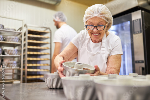 Ältere Bäckerin beim Backen von Gugelhupf Kuchen photo