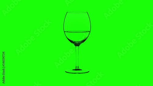Empty glass filling up with expensive sweet sparkling wine to half made of ripe grapes on bright green background closeup