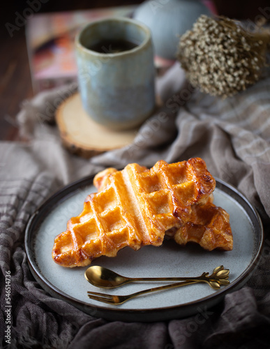 2 piece of croffles, serve in ceramic plate with a cup of tea on wood table, nature light, food issue, selective focus.