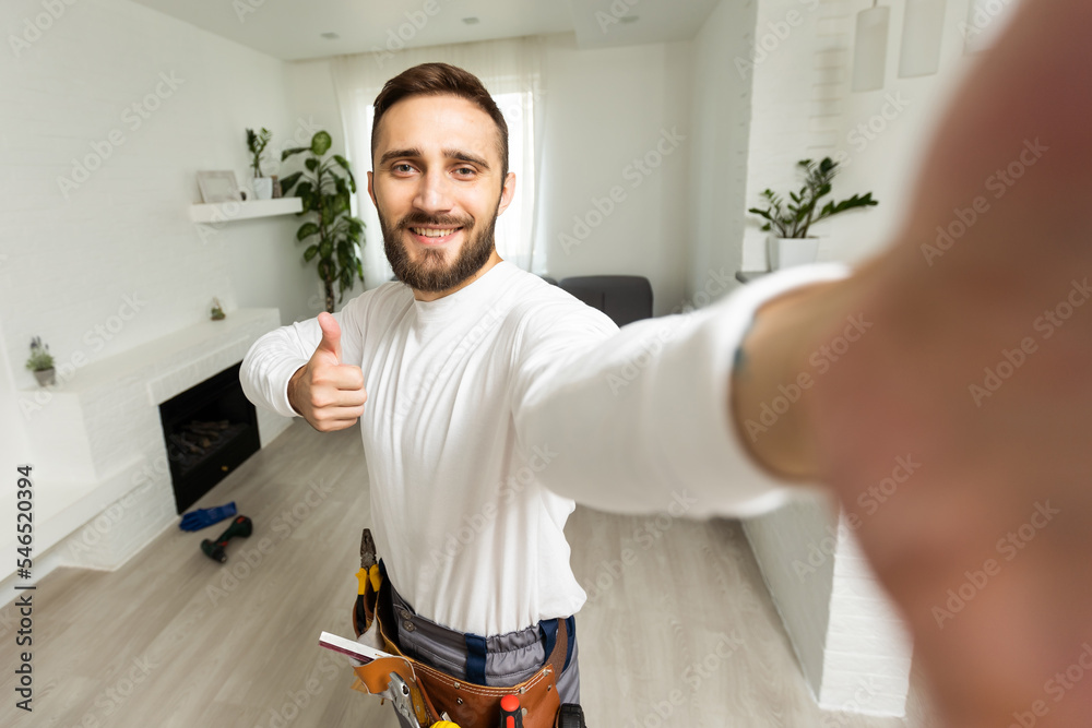 Portrait of handsome cheerful repairer shooting selfie on smart phone, wearing shirt and overalls Portrait of handsome cheerful repairer shooting selfie on smart phone, wearing shirt and overalls