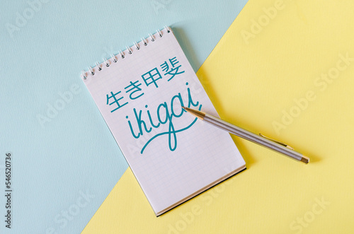 ikigai inscription in English and Chinese in a notebook on a yellow-blue background. ikigai - Japanese philosophy and life style - a reason for being  photo