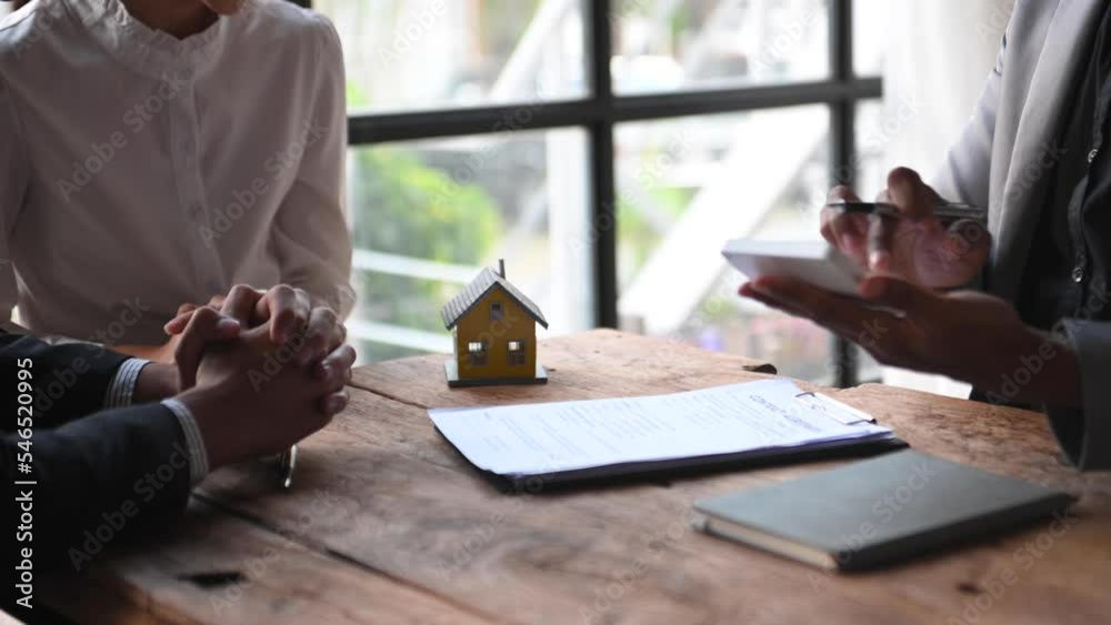 Real estate broker agent presenting and consult to customer to decision making sign insurance form agreement, home model, concerning mortgage loan offer in office.