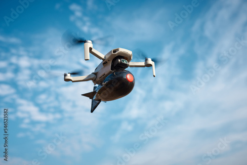 consumer civilian drone with a big bomb on board flies in the blue sky