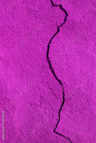 Vertical photograph of a pink painted wall with a large crack from top to bottom