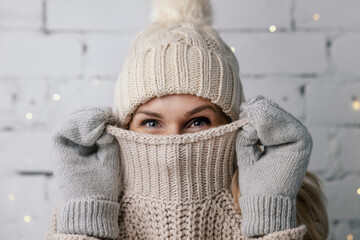 woman hiding face in wool winter sweater. cold weather clothes