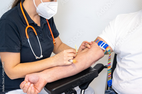 Arzthelferin nimmt einem Patienten Blut ab