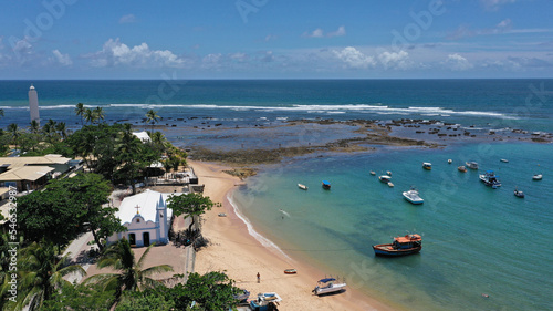 Panoramic view of Praia do Forte beach near Salvador city with fishing boats, palm trees and a historic church. Praia do Forte, Bahia State, Brazil 