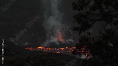 Smoldering erupted volcano with red hot magma on the ground with rising smoke in the dark surrounding