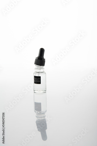 Szklana fiolka z pipetą, bezbarwnym płynem i etykietą z napisem beauty serum