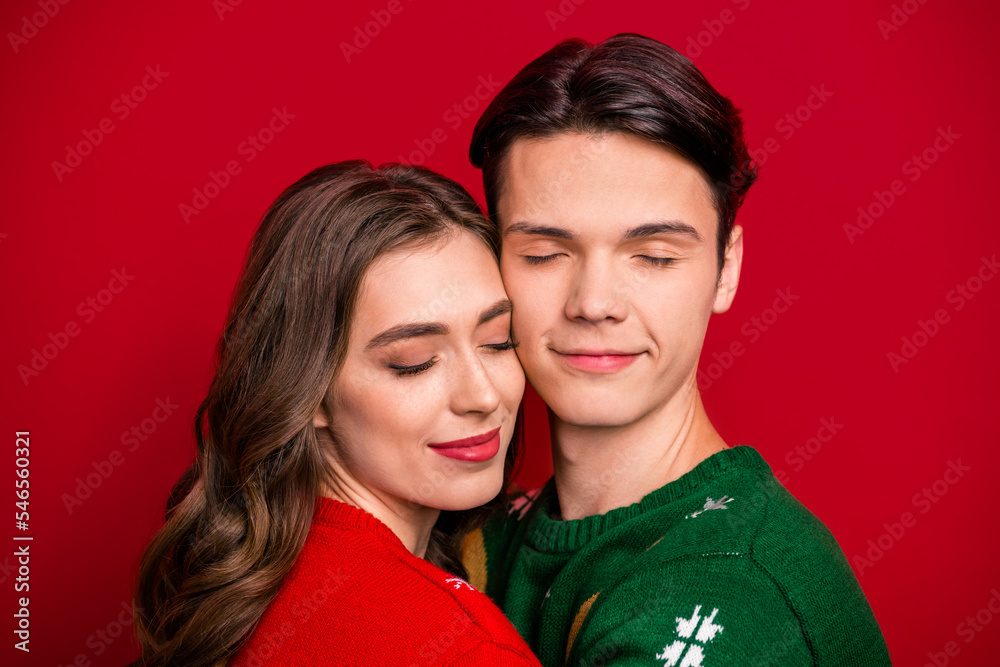 Photo of dreamy adorable husband wife wear xmas sweaters embracing closed eyes isolated red color background Photo of dreamy adorable husband wife wear xmas sweaters embracing closed eyes isolated red color background