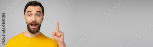 excited bearded man showing idea gesture while looking at camera isolated on grey, banner.
