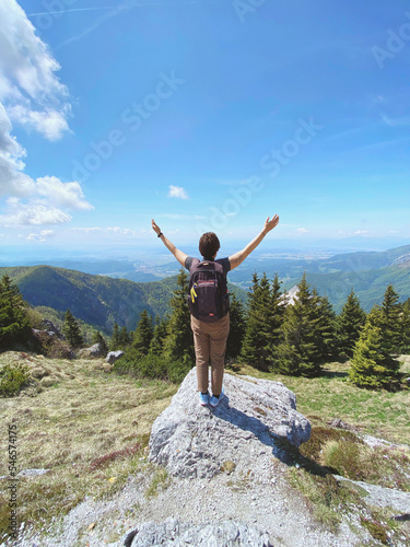 Woman enjoys views of the alpine village in the mountains. Velika Planina or Big Pasture Plateau in the Kamnik Alps, Slovenia. Mountain cottage hut or house.