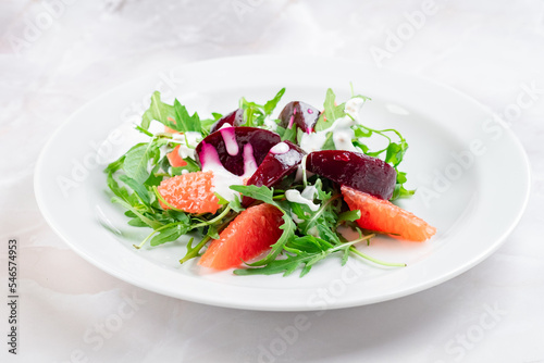 Salad with boiled beetroot, grapefruit, arugula and cream cheese. Beetroot slices with green salad