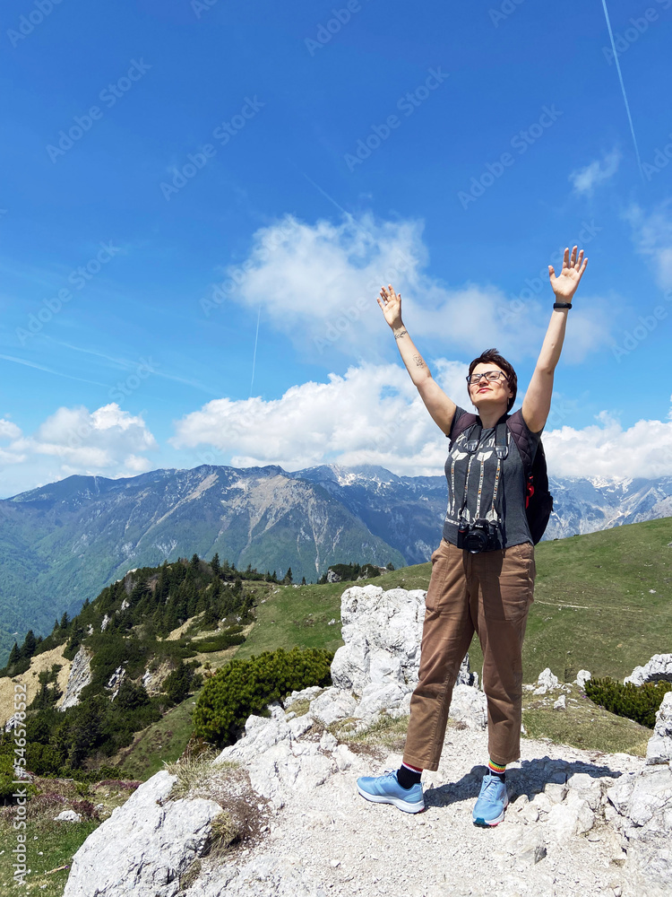 Woman enjoys views of the alpine village in the mountains. Velika Planina or Big Pasture Plateau in the Kamnik Alps, Slovenia. Mountain cottage hut or house. Woman enjoys views of the alpine village in the mountains. Velika Planina or Big Pasture Plateau in the Kamnik Alps, Slovenia. Mountain cottage hut or house.