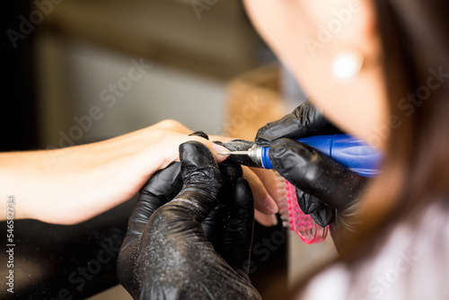 A manicure master does a hardware manicure to a client in a beauty salon. Beauty industry.