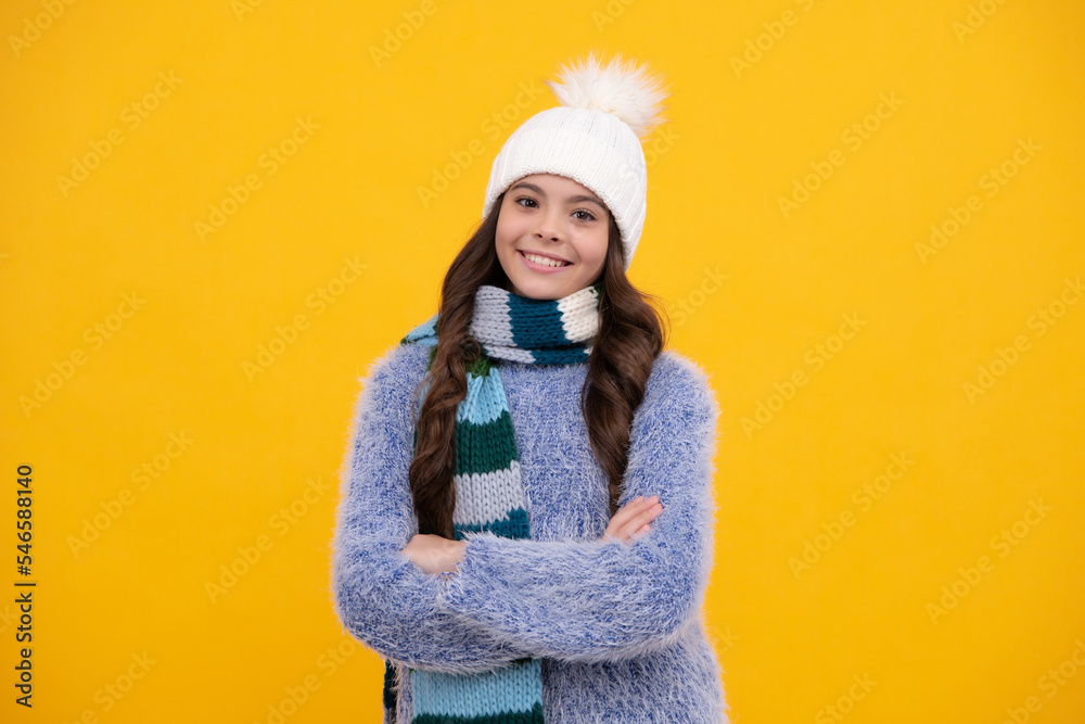 Modern teen girl wearing sweater and knitted hat on isolated yellow background. Happy girl face, positive and smiling emotions.