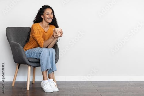 Cheerful young middle eastern woman drinking coffee, copy space