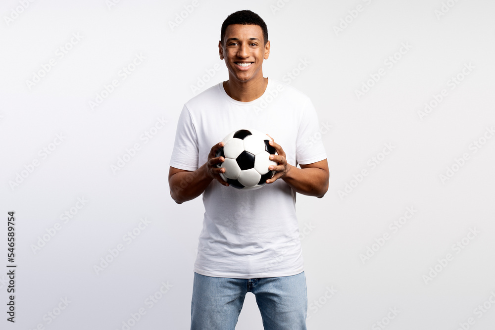 Portrait of handsome man holding soccer ball at his hands with smiling positive expression
