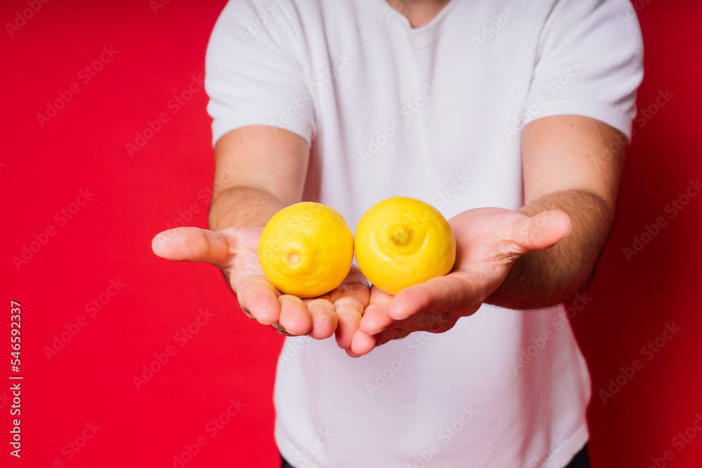 Portrait of young bearded man holding lemons in both hands on isolated red background Portrait of young bearded man holding lemons in both hands on isolated red background