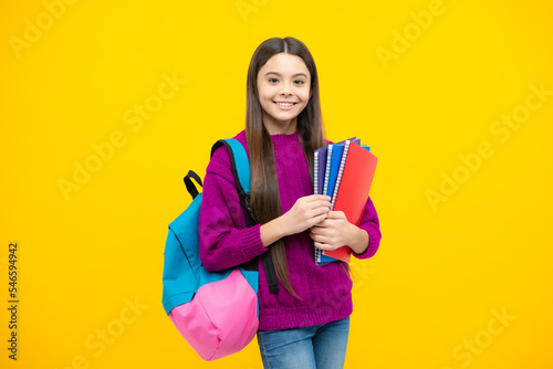 Back to school. Teenager schoolgirl hold book and copybook ready to learn. School children on isolated yellow studio background.