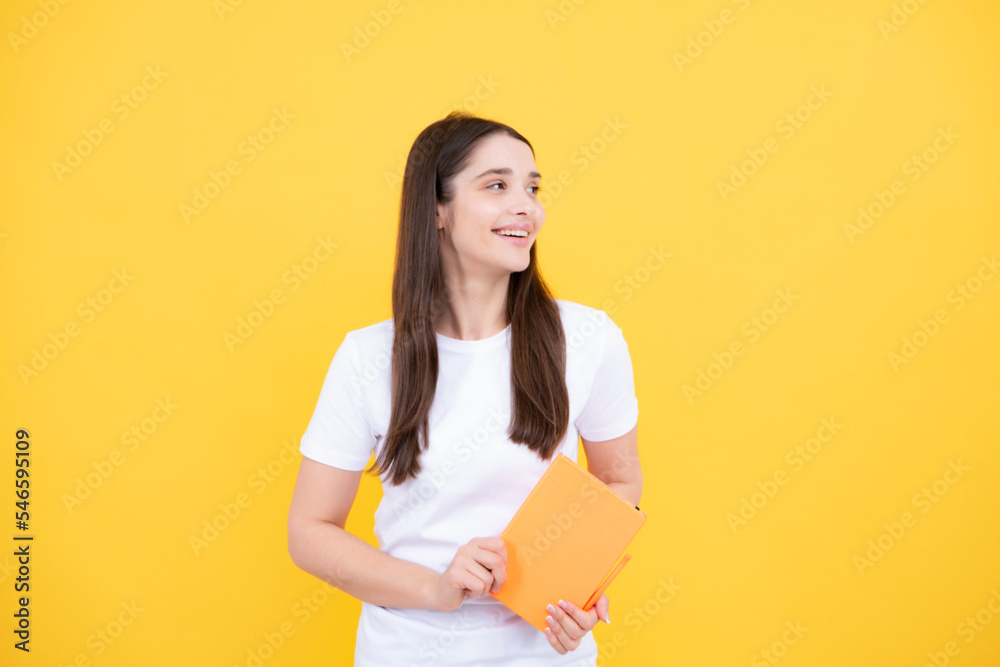 Teenager student girl isolated on yellow background. Cheerful young woman student in shirt hold notebooks showing. High school university college students. Teenager student girl isolated on yellow background. Cheerful young woman student in shirt hold notebooks showing. High school university college students.
