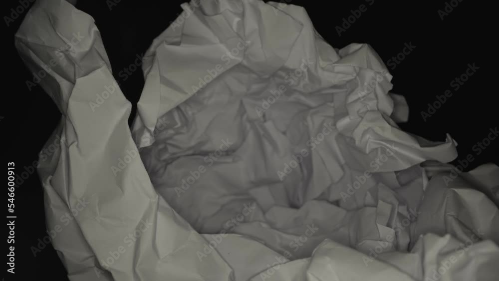 Large sheet of white crumpled paper material as writing failure symbol on black background in studio extreme close view zoom in