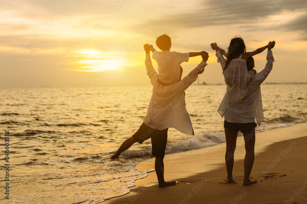Fototapeta premium Happy asian family on the beach in holiday. of the family holding hands, Son and daughter piggyback on parents.They are having fun playing enjoying the sunset on the beach. Summer Family and lifestyle