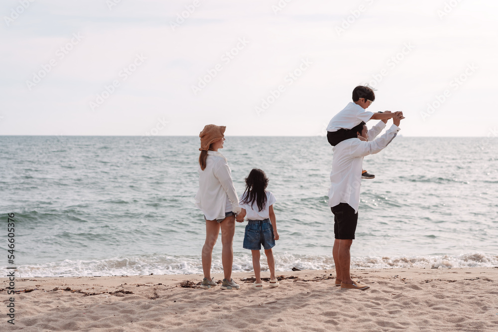Happy asian family on the beach in holiday. of the family holding hands, Son and daughter piggyback on parents.They are having fun playing enjoying on the beach. Summer Family and lifestyle concept.