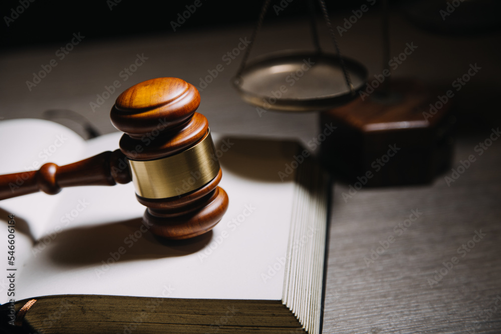 Justice and law concept.Male judge in a courtroom with the gavel, working with, computer and docking keyboard, eyeglasses, on table in morning light