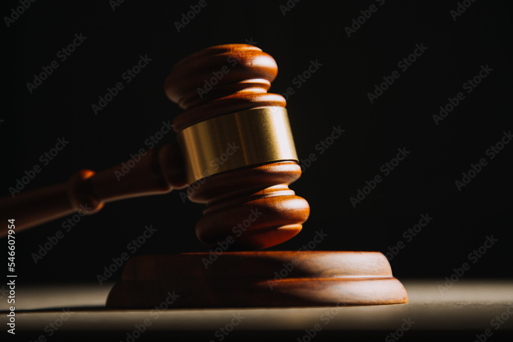Justice and law concept.Male judge in a courtroom with the gavel, working with, computer and docking keyboard, eyeglasses, on table in morning light Justice and law concept.Male judge in a courtroom with the gavel, working with, computer and docking keyboard, eyeglasses, on table in morning light