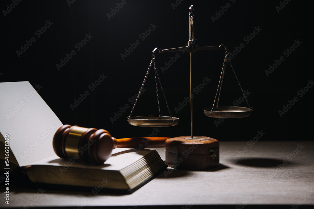 Justice and law concept.Male judge in a courtroom with the gavel, working with, computer and docking keyboard, eyeglasses, on table in morning light Justice and law concept.Male judge in a courtroom with the gavel, working with, computer and docking keyboard, eyeglasses, on table in morning light