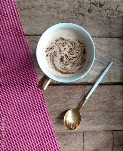 cup of coffee and spoon on wood and pink background 