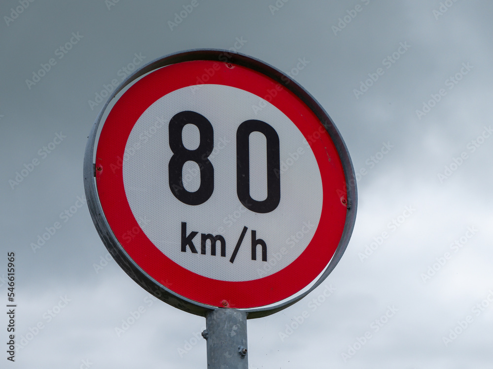A road sign limiting the speed of 80 km per hour. A road sign against a cloudy sky.