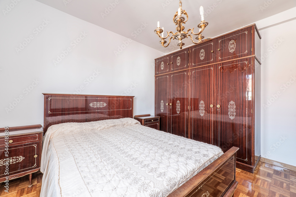 Furnished bedroom with vintage light wood furniture set with white bedspread and parquet floor