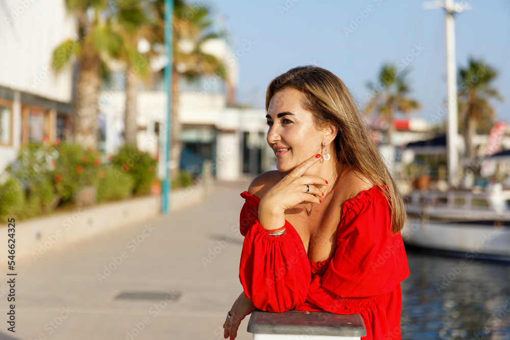 Fototapeta premium Portrait of a beautiful woman on the background of the blue sea and yachts
