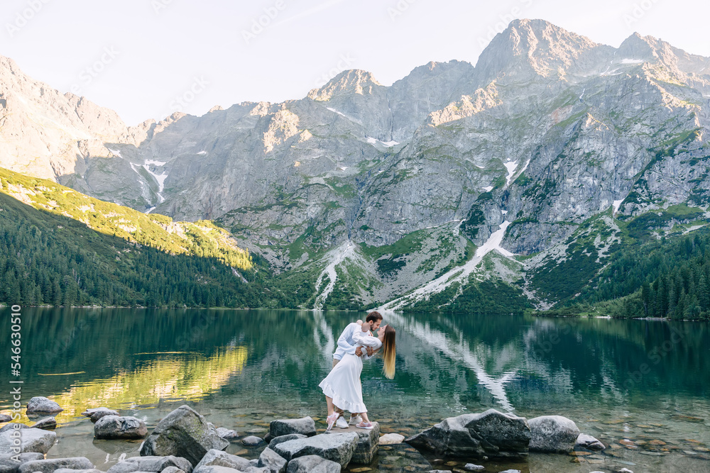 Φωτογραφία the guy hugs the girl and she bend back. couple on rocky shore o
