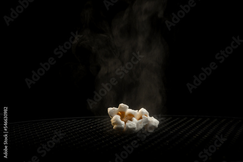 Hot popcorn with smoke.
Popcorn close-up on a black background.
A macro shot of a popcon in a couple. photo