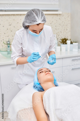 beautician applies the mask to face of beautiful woman