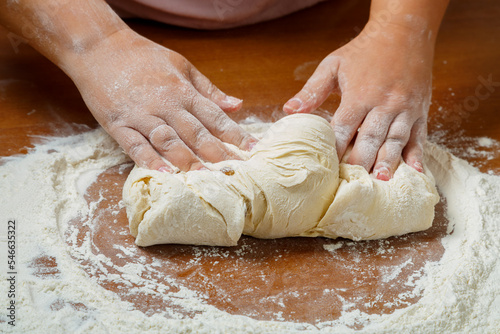 The hands of a Jewish woman knead the dough for wicker challahs for the holiday.