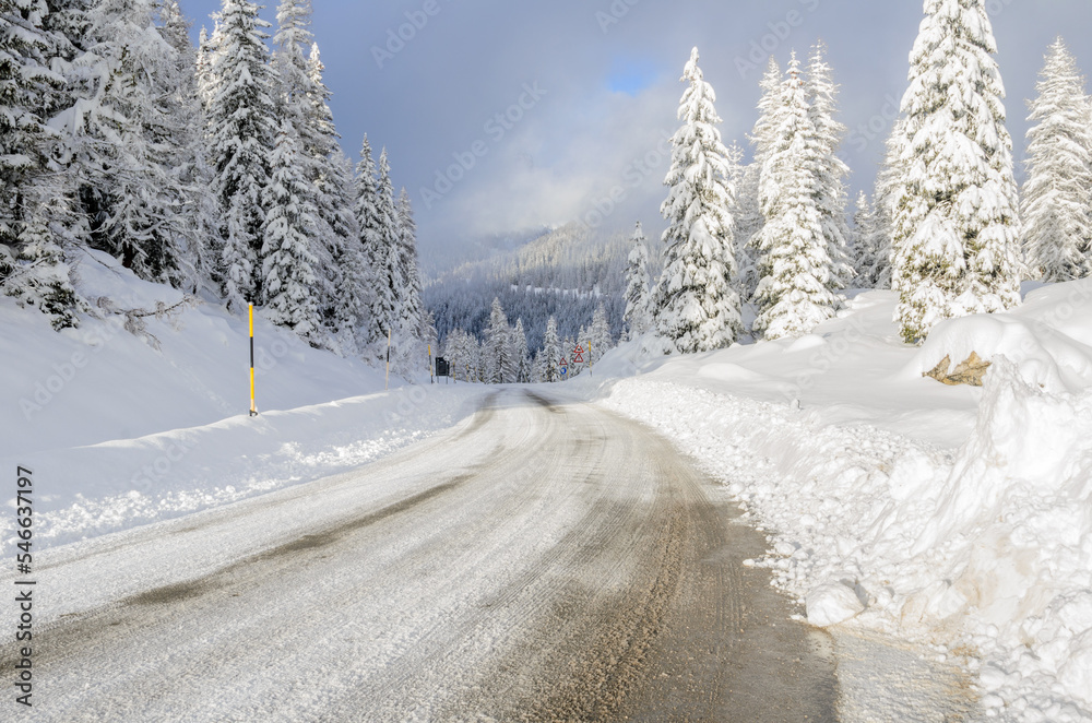Snow covered mountain pass road through a snowy forest in winter