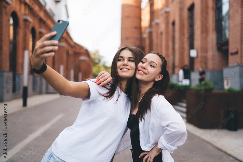 Cheerful women taking selfie in city