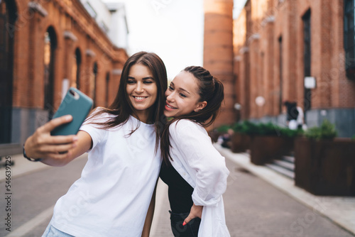 Cheerful women taking selfie on street