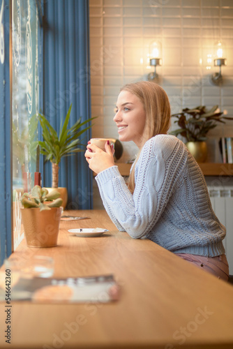 Side view of thoughtful woman having drink at table in cafe during Christmas