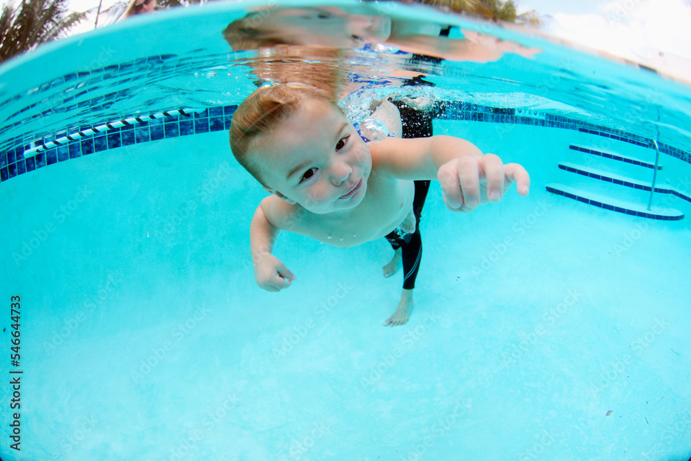 Foto de A young boy swimming underwater in a pool during an infant swim