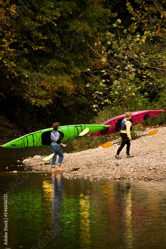 2 middle-aged women carry sea-kayaks from Farmington River near Collinsville, Connecticut, USA. photo