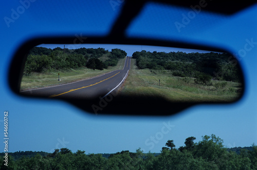 View in rear view car mirror of road through the Texas Hill Country. photo